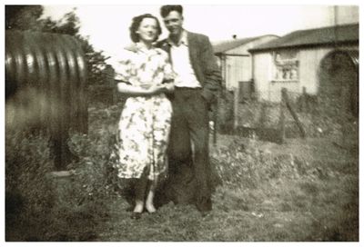Mom and Dad in front of prefabs

